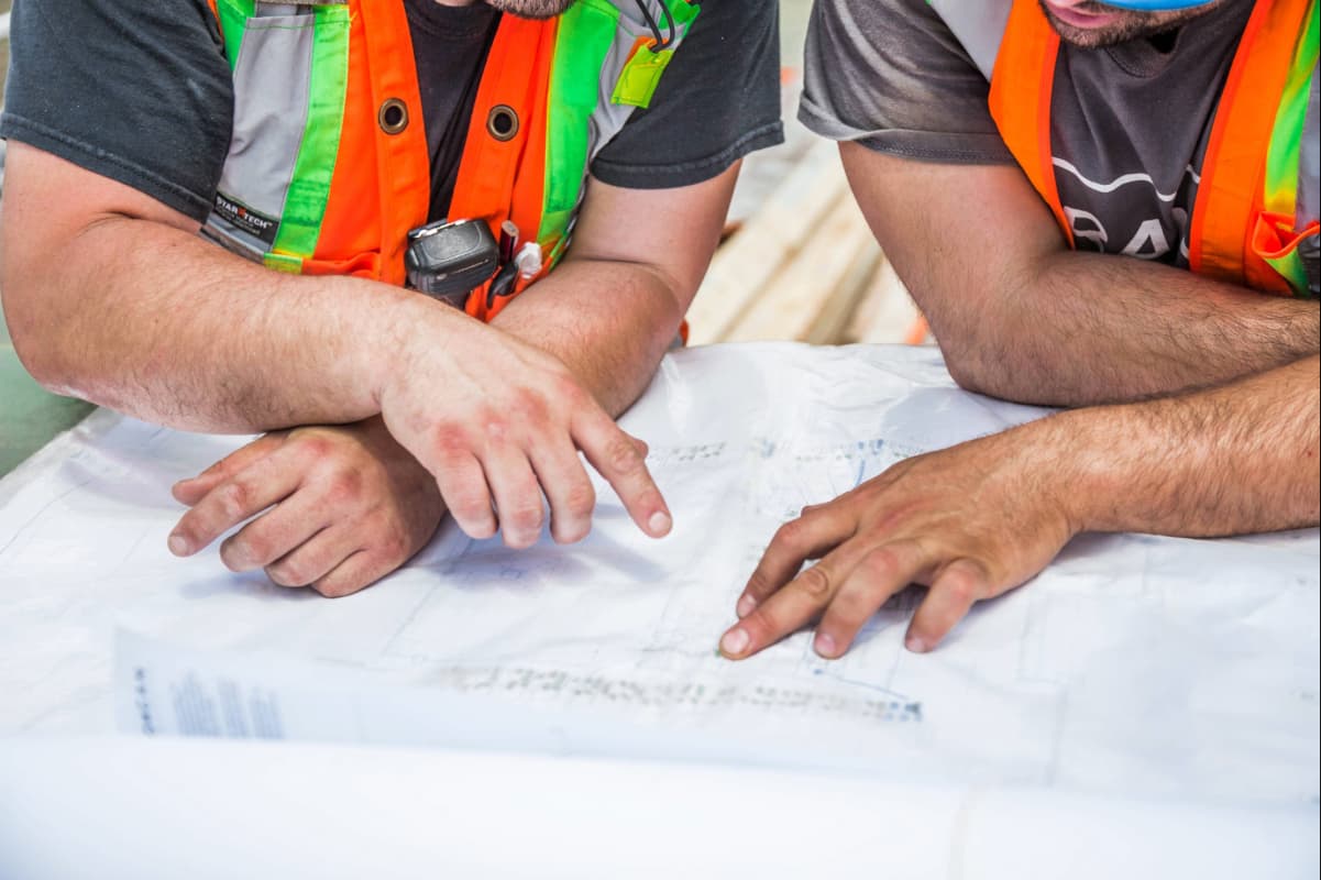 Deux professionnels de la construction consultent ensemble des plans posés sur une table.